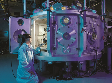 A woman in a lab coat standing next to a large machine in a laboratory.