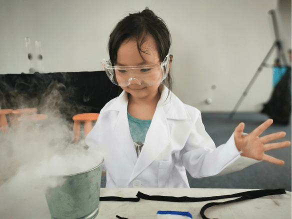 Girl wearing lab coat and goggles conducting an experiment to create a cloud