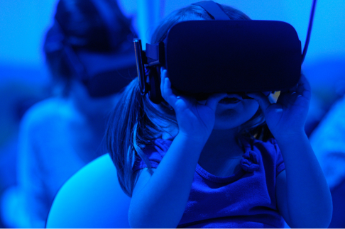 A young girl immersed in a virtual reality experience with a headset on, exploring a digital world.