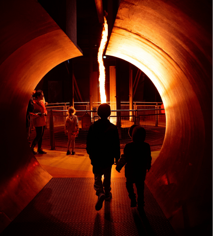 Two children walking towars the fire energy exhibition at night