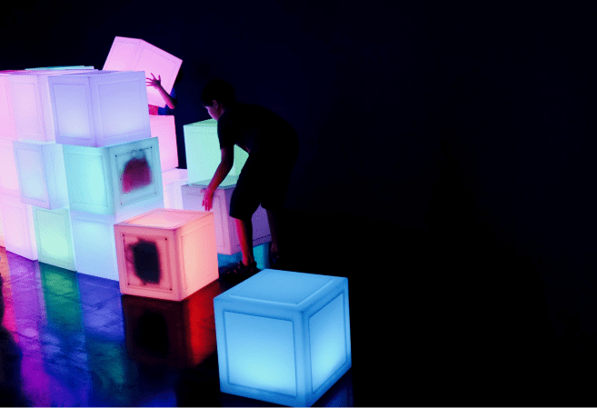 Children playing with neon glow boxes in a dark room